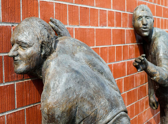 Picture of statue figures listening through wall