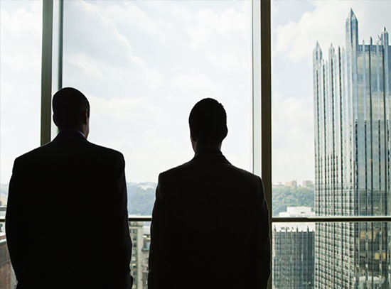 silhouette of men looking out office window